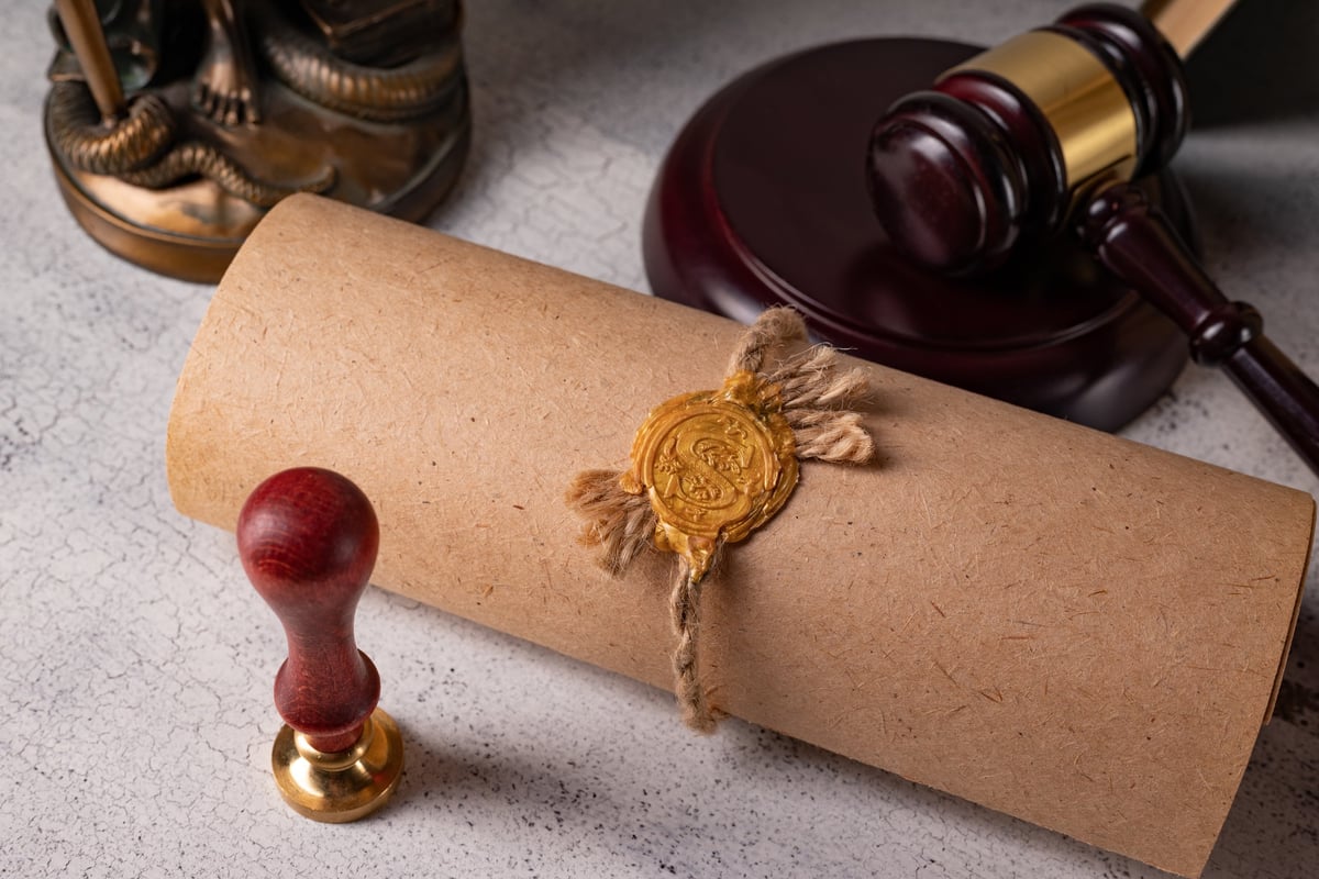 Judge's gavel, books, parchment scroll with seal and stamp on an old wooden table